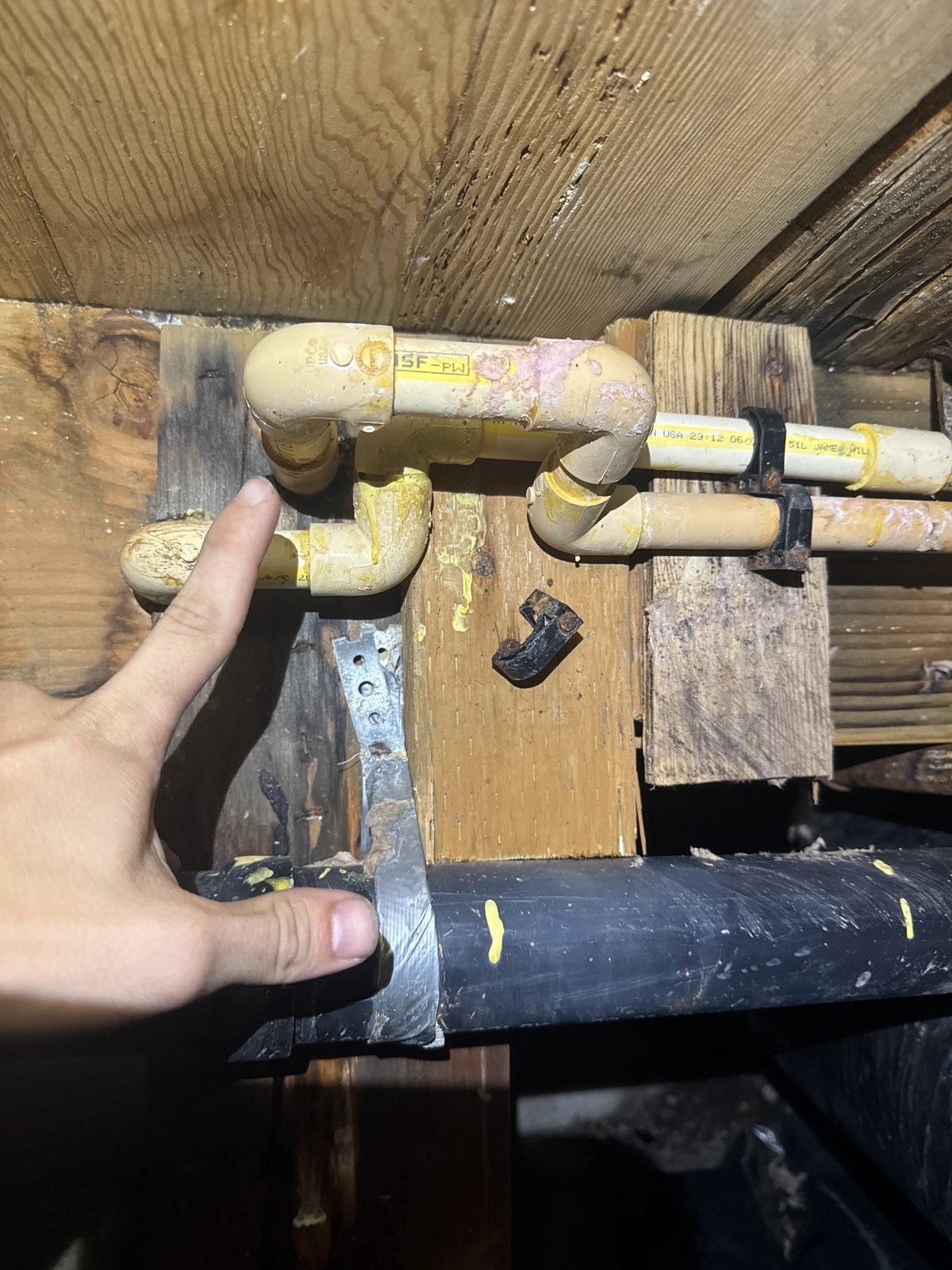 Aged CPVC fittings in a crawlspace with mineral deposits and previous repair attempts
